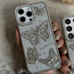 قاب موبایل ( آیفون - سامسونگ ) پروانه آموره نگین دار برجسته شاینی + بندست